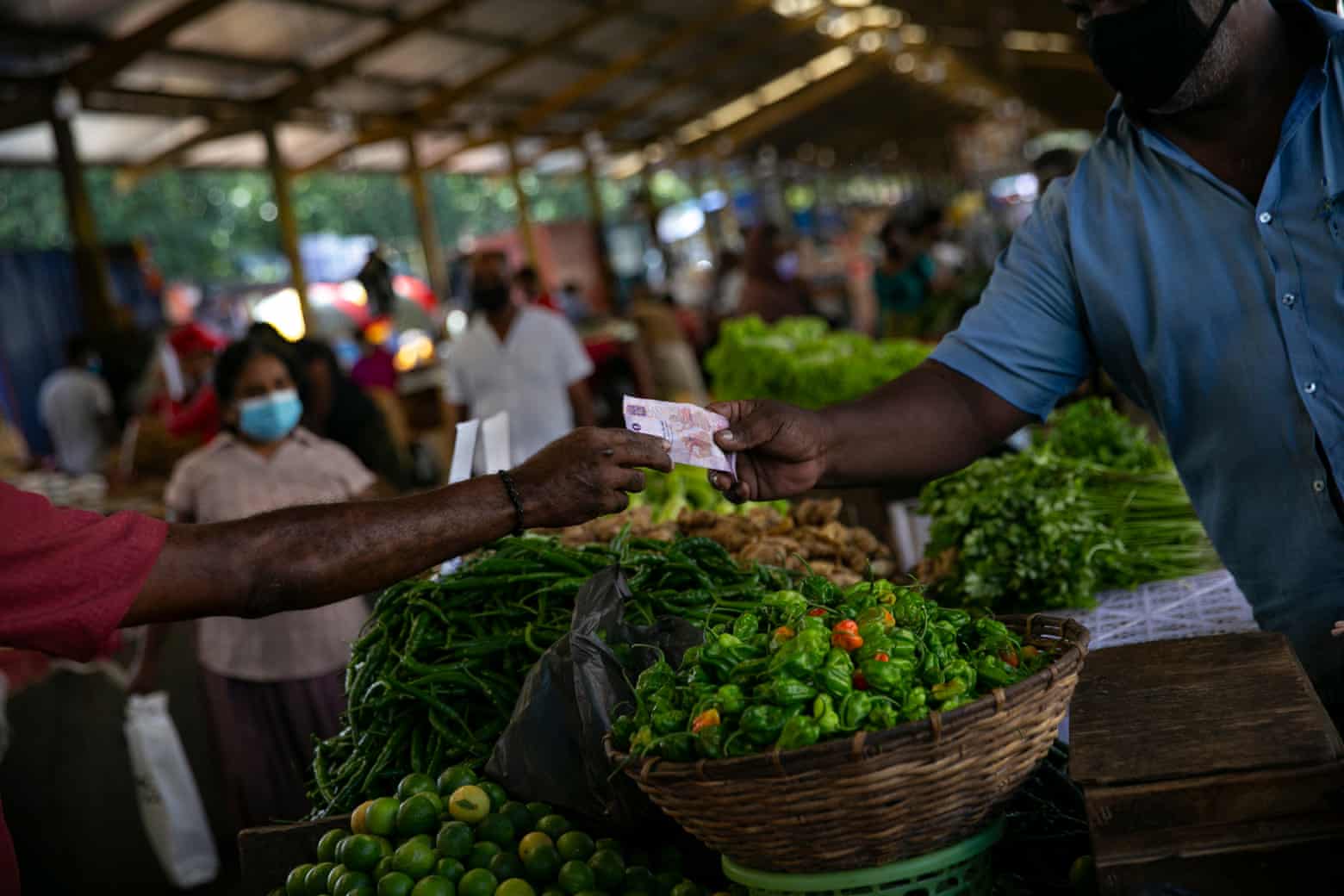 Một người đàn ông trả tiền mua rau tại chợ ở Colombo. Giá cả leo thang đã khiến những người trước đây khá giả phải vật lộn để nuôi sống gia đình của họ. Ảnh: Allison Joyce