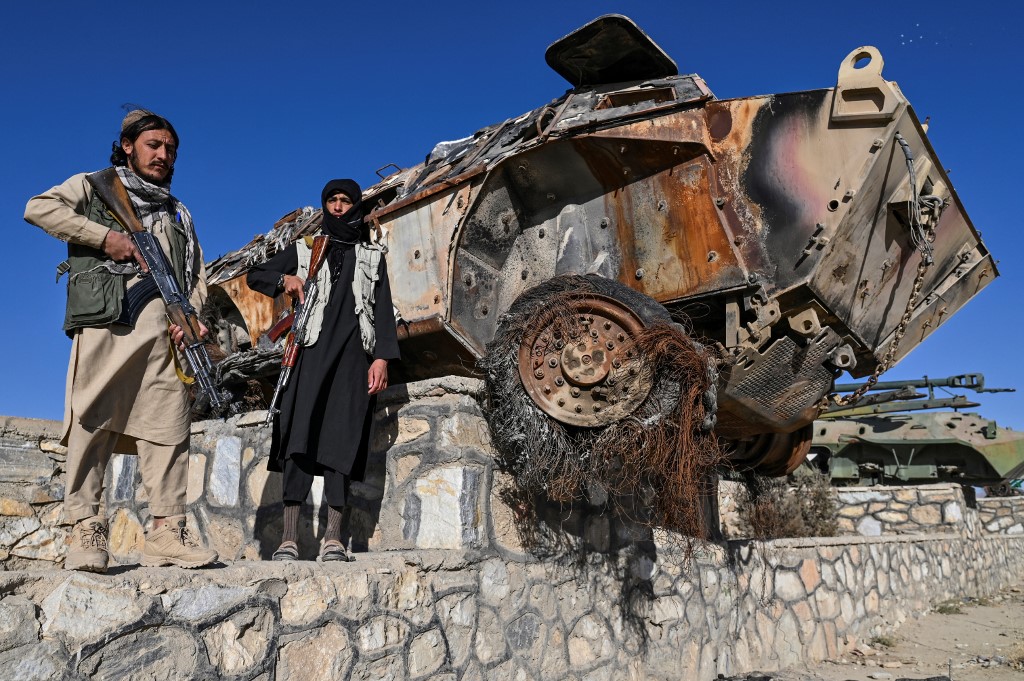 Thành viên Taliban đứng cạnh xác thiết giáp ở tỉnh Ghazni hồi tháng 11/2021. Ảnh: AFP.