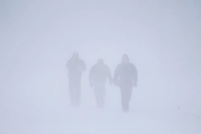 Ba người đàn ông đi bộ xuống Đại lộ Richmond khi trận bão tuyết kéo dài ở Buffalo ngày 24/12. Ảnh: AFP.