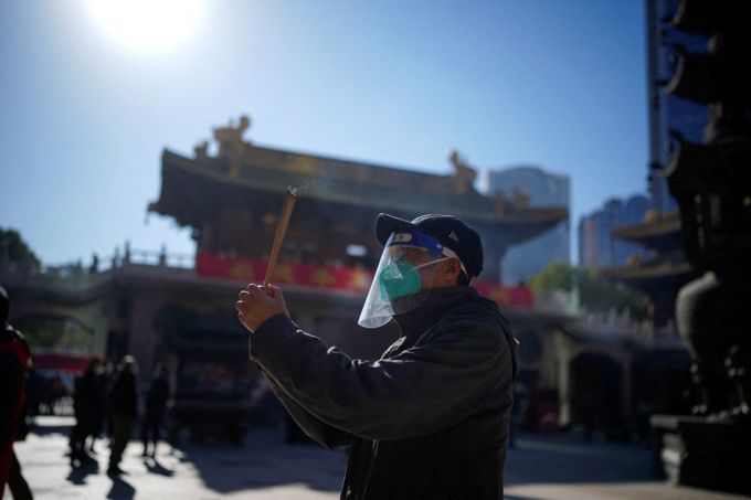 Người đàn ông đeo khẩu trang và tấm chống giọt bắn hành lễ tại một ngôi chùa ở Thượng Hải, Trung Quốc hôm 23/12/2022. Ảnh: Reuters.