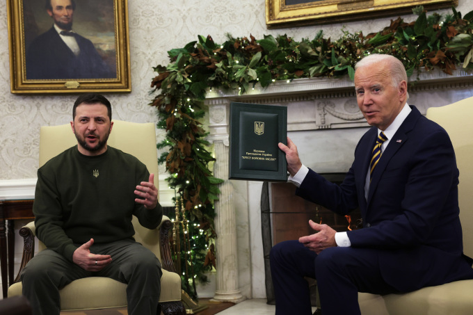 Tổng thống Ukraine Volodymyr Zelensky chuyển quà từ một binh sĩ nước này cho Tổng thống Mỹ Joe Biden tại Nhà Trắng ngày 21/12. Ảnh: AFP.