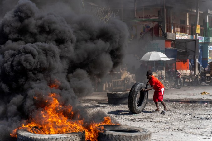 Cảnh sát chống bạo động mặc thường phục đốt lốp xe trong cuộc bạo loạn phản đối các băng đảng giết hại nhân viên thực thi pháp luật ở Port-au-Prince, Haiti, ngày 26/1. Ảnh: AFP