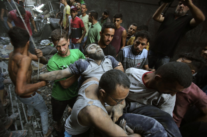Người đàn ông bị thương được đưa khỏi đống đổ nát sau vụ không kích của Israel tại thành phố Gaza ngày 12/10. Ảnh: AFP