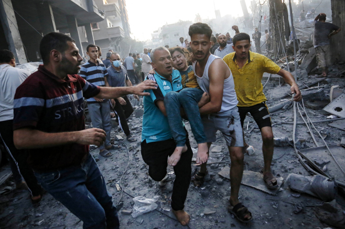 Nhóm người di chuyển bé gái bị thương sau một cuộc tập kích của Israel ở Dải Gaza hồi tháng 10 năm ngoái. Ảnh: AFP