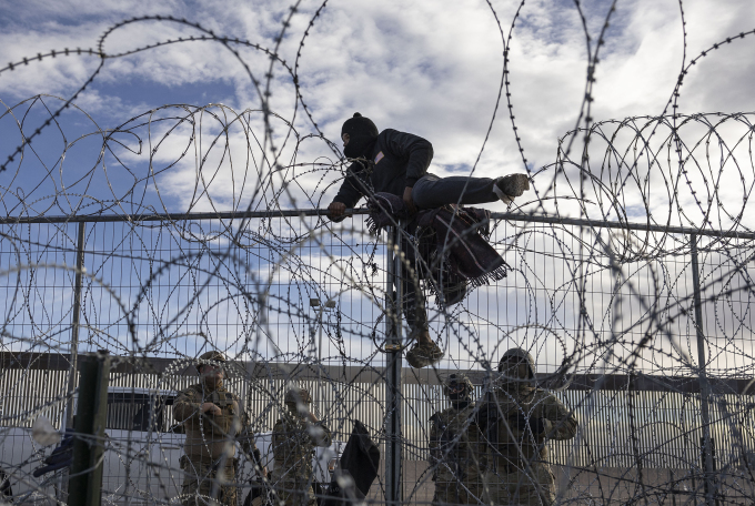 Người nhập cư trèo qua hàng rào từ Ciudad Juarez, Mexico vào El Paso, bang Texas, Mỹ ngày 2/4/2024. Ảnh: AFP