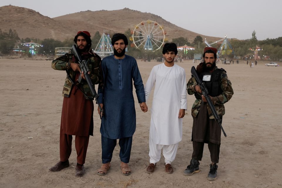 Hai khách tham quan (giữa) chụp ảnh với lính Taliban tại một công viên giải trí tỉnh Wardak, Afghanistan tháng 10/2021. Ảnh; Reuters.