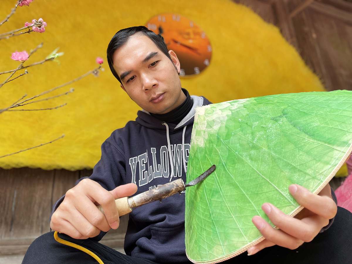 Anh Kiều Cao Dũng đang dùng một vật để là cho nón lá bồ đề phẳng, đẹp, tại cơ sở chằm nón ở xã Phú Mỹ, huyện Quốc Oai một ngày cuối năm 2021. Ảnh: Phan Dương