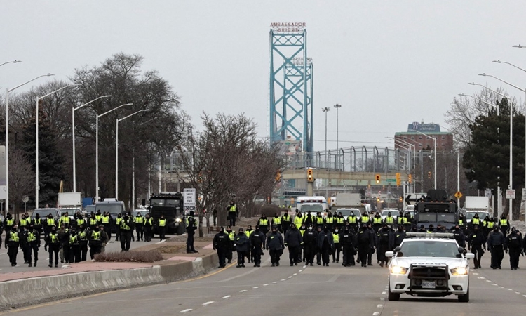 Cảnh sát tập trung giải tán hết đoàn xe biểu tình chặn Cầu Ambassador ở thành phố Windsor, Ontario, Canada, hôm 13/2. Ảnh: AFP.