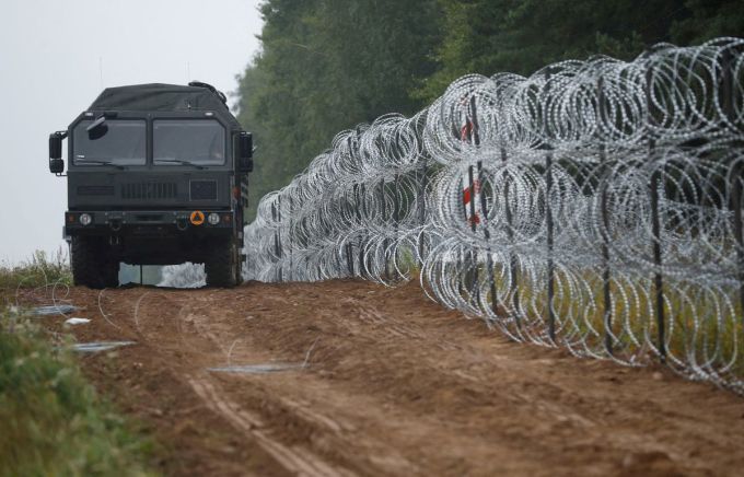 Chiếc xe cạnh hàng rào do binh lính Ba Lan dựng ở biên giới với Belarus, gần làng Nomiki, Ba Lan năm 2021. Ảnh: Reuters.