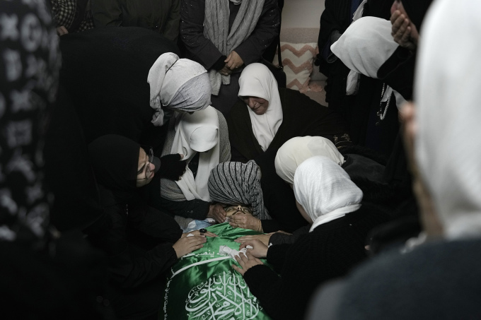 Những người phụ nữ Palestine ngồi quanh thi thể Muhammad Jalamneh được phủ cờ Hamas trong nhà xác bệnh viện Ibn Sina ngày 30/1. Ảnh: AP