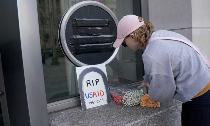 Một người để lại hoa bên cảnh bức vẽ với thông điệp USAID yên nghỉ tại trụ sở chính của cơ quan này ở Washington, ngày 7/2. Ảnh: Reuters
