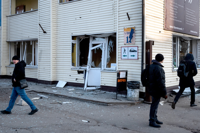 Người dân Kiev đi bộ qua một dãy nhà bị không kích, ngày 12/2. Ảnh: AFP