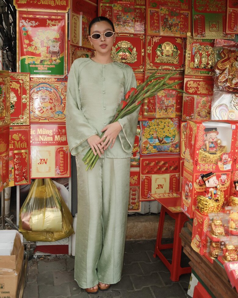 Gam xanh ngọc mát mắt cũng là lựa chọn đầy tinh tế cho dịp Tết. Áo bà ba dáng rộng, hàng nút vải cổ điển, tay loe nhẹ giúp tổng thể bay bổng, phù hợp với không khí Xuân. Khi kết hợp cùng túi cói và giày sandal, trang phục mang tinh thần nghỉ dưỡng, trẻ trung.