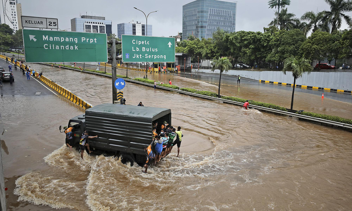 Xe quân sự chở dân thường ra khỏi khu vực bị ngập sau mưa lớn ở Jakarta, Indonesia ngày 20/2. Ảnh: AP.