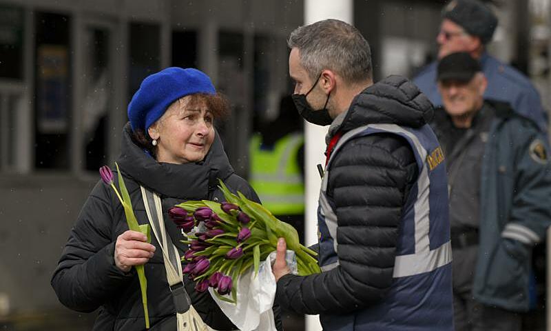 Một nhân viên nhập cảnh Romania tặng hoa cho người tị nạn Ukraine ở biên giới ngày 8/3. Ảnh: AP.