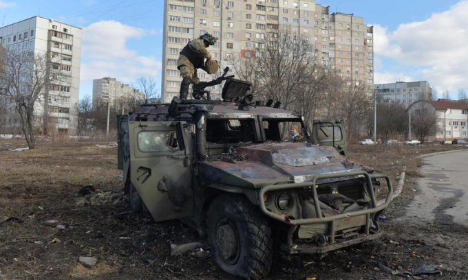 Một lính Ukraine kiểm tra chiếc xe đã bị phá hủy ở thành phố Kharkov, Ukraine hôm 27/2. Ảnh: AFP.