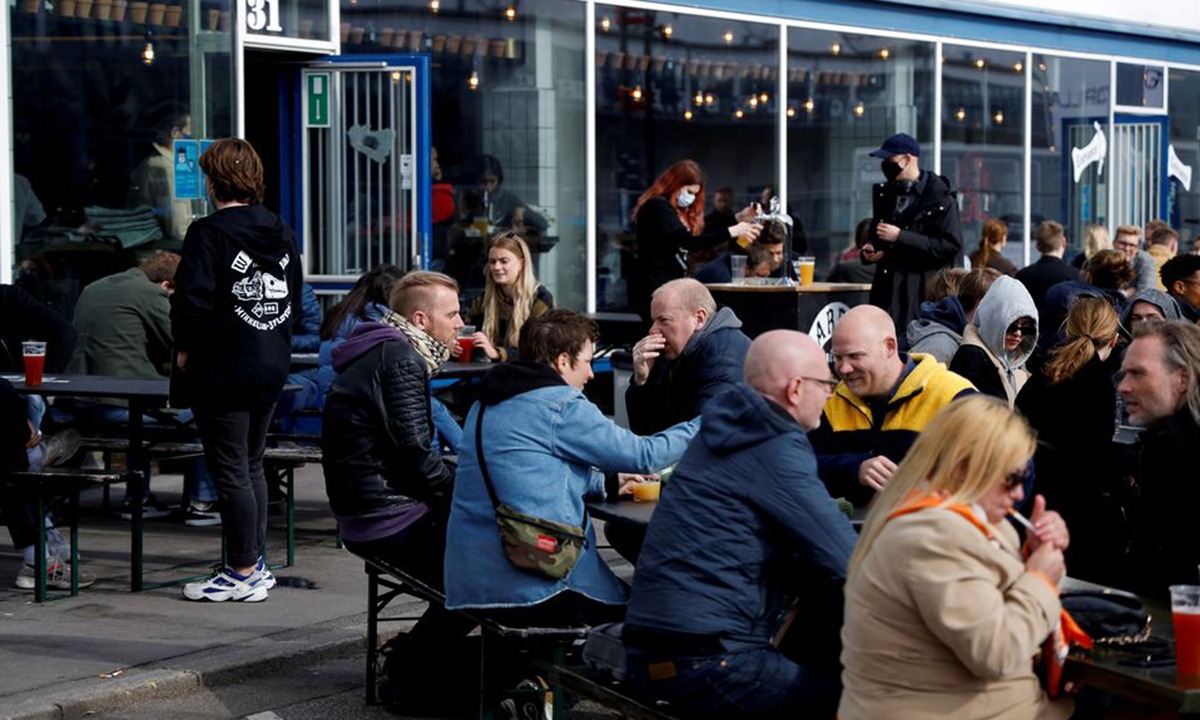 Người dân ngồi tại quán cà phê ở Copenhagen, Đan Mạch hồi tháng 4/2021. Ảnh: Reuters.