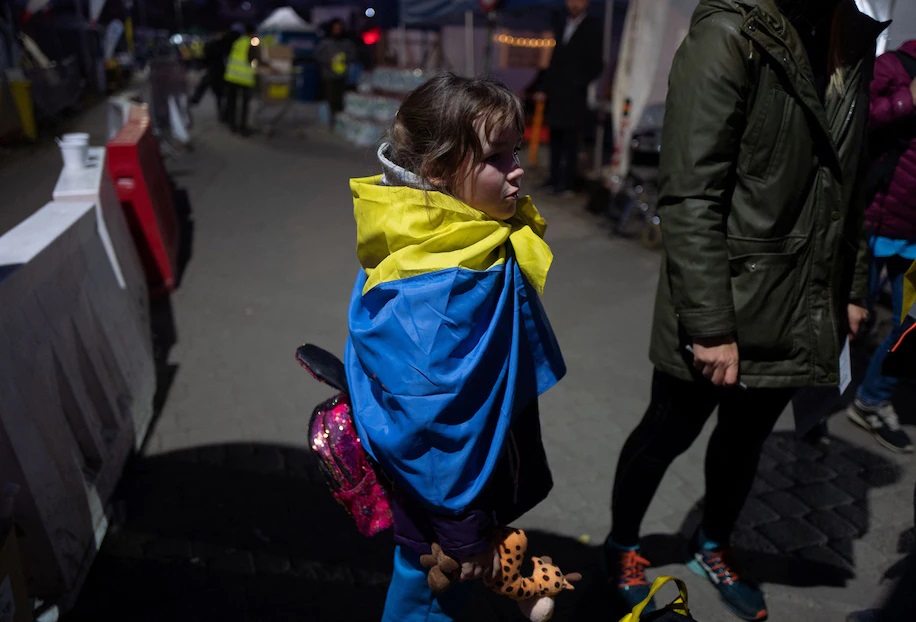 Bé gái người Ukraine quấn quốc kỳ quanh người khi tới biên giới Ba Lan hôm 23/3. Ảnh: Reuters.