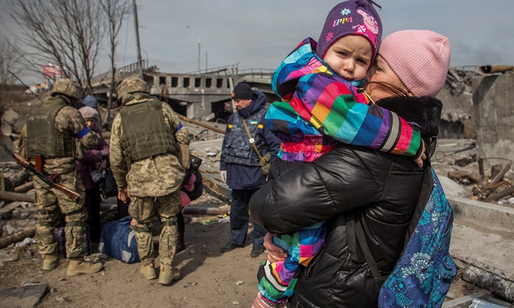 Một phụ nữ bế theo em nhỏ khi đi sơ tán khỏi Irpin, Ukraine, hôm 28/3. Ảnh: Reuters.