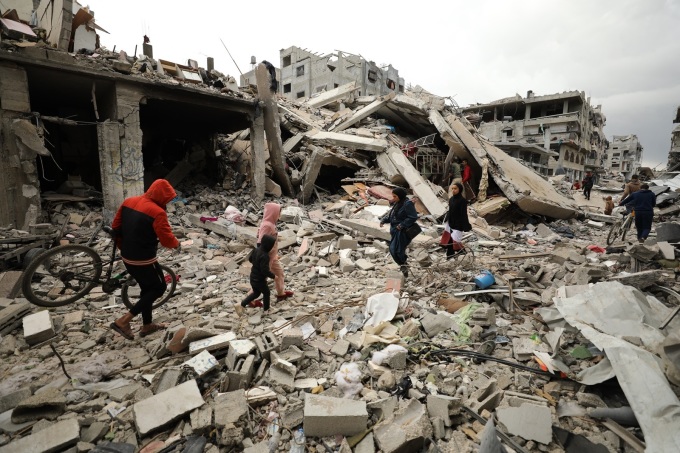 Người dân đi qua các tòa nhà đổ nát do những cuộc tấn công của Israel ở Gaza City ngày 7/3. Ảnh: AFP