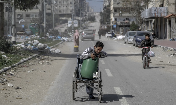 Một cậu bé dùng xe lăn để chuyển nước ở Gaza City hôm 3/3. Ảnh: AFP