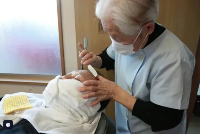 Bà Hakoishi cắt tóc cho khách ở tiệm. Ảnh: Weixin