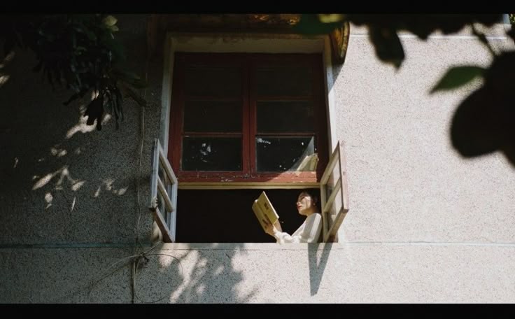 Có thể có: một người phụ nữ đang đọc sách trong khi nhìn ra ngoài cửa sổ