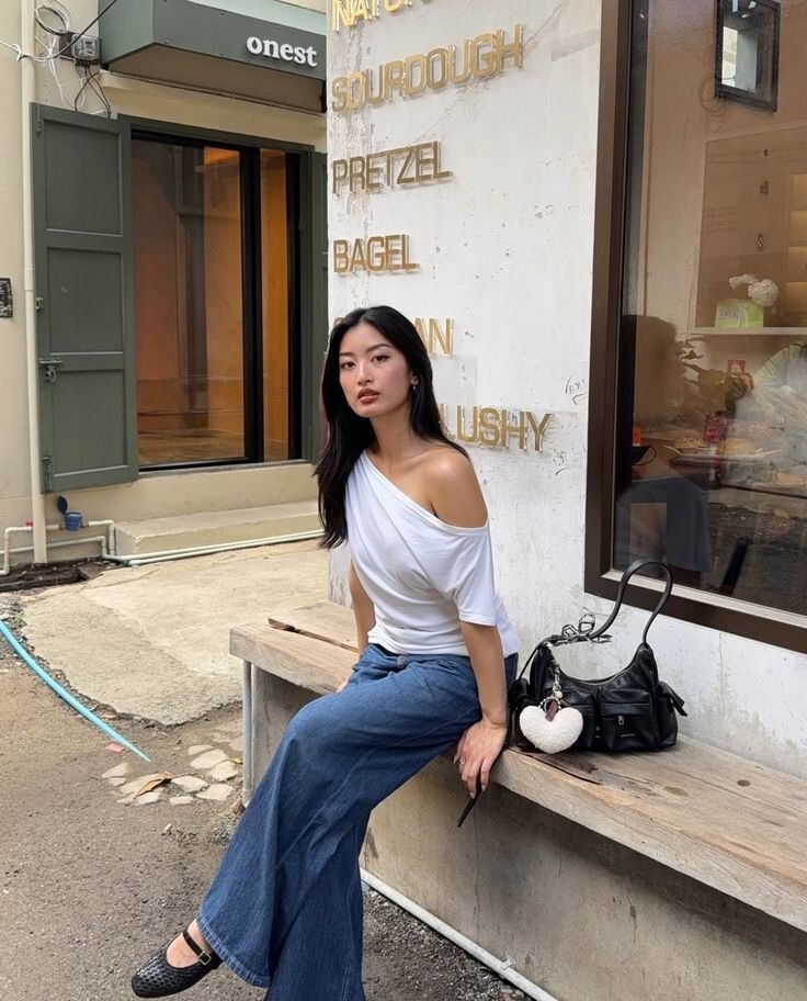 Sự kết hợp giữa áo lệch vai mềm mại và quần jeans năng động tạo tổng thể cân bằng. Jeans dáng suông hoặc ống đứng giúp outfit hiện đại, dễ mặc. Chỉ cần áo trơn màu và jeans basic là đã đủ tạo vẻ ngoài đơn giản nhưng vẫn rất có gu.