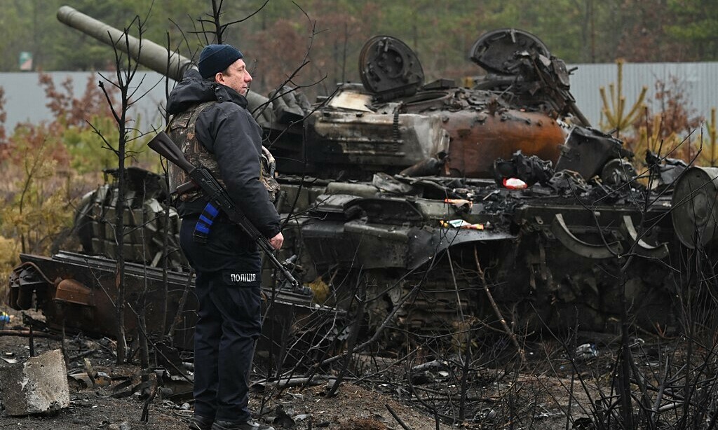 Cảnh sát Ukraine canh gác cạnh một xác xe tăng ở làng Dmytrivka, phía tây Kiev ngày 2/4. Ảnh: AFP.