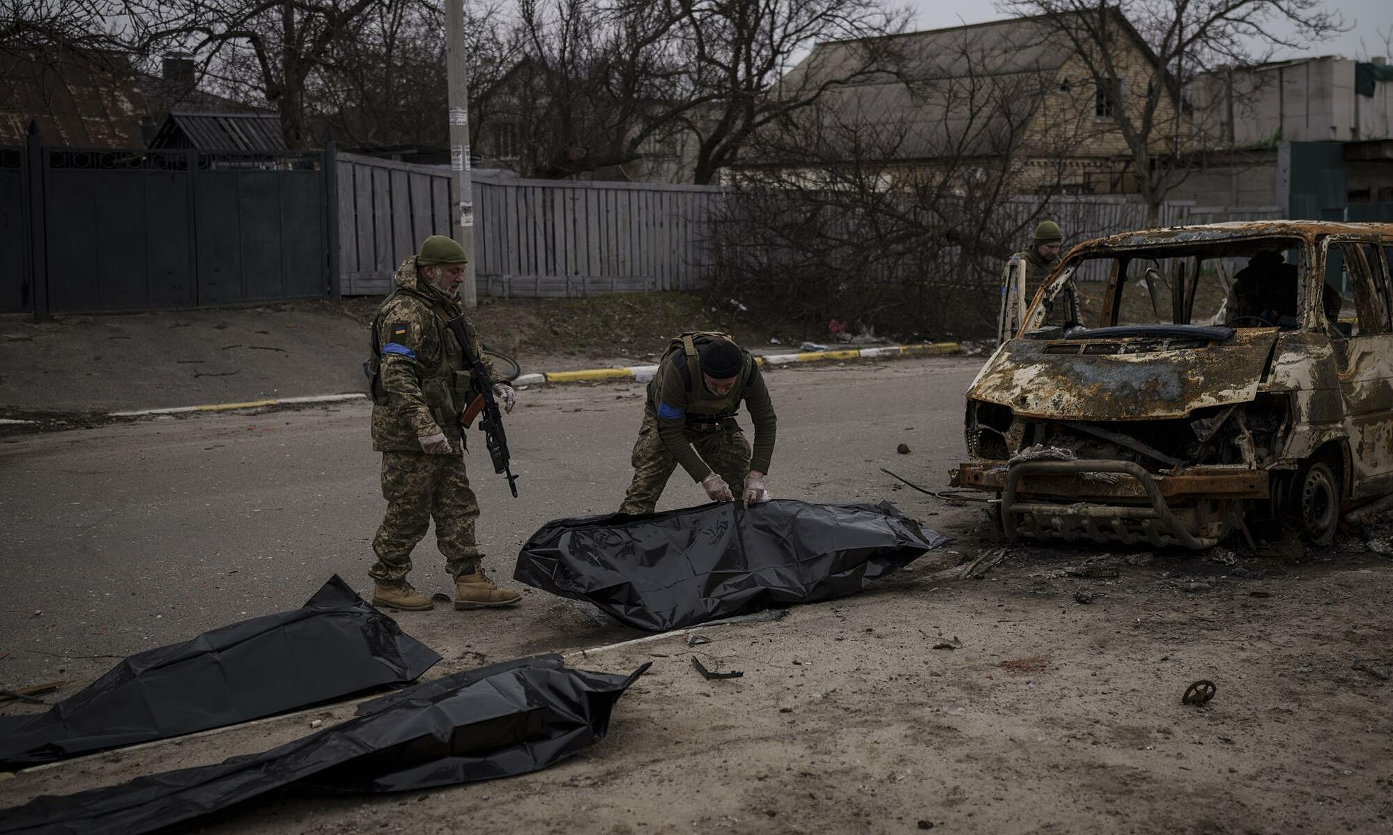 Binh lính Ukraine thu dọn các túi được cho đựng thi thể dân thường thiệt mạng tại Bucha, Ukraine hôm 5/4. Ảnh: AP.