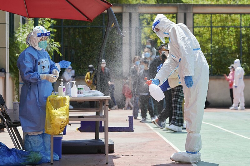 Nhân viên chống dịch phun khử khuẩn trước khi tiến hành xét nghiệm hàng loạt tại quận Phố Đông, Thượng Hải hôm 17/4. Ảnh: AFP.