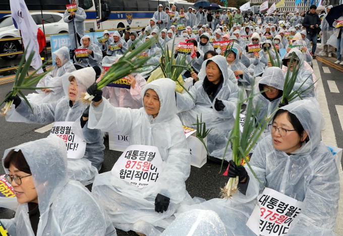 Nông dân Hàn Quốc vẫy hành lá kèm biểu ngữ  Lương tháng của tổng thống chỉ đáng 875 won, trong cuộc biểu tình phản đối nông sản nhập khẩu ngoài trụ sở chính phủ ở Sejong ngày 25/3. Ảnh: AFP