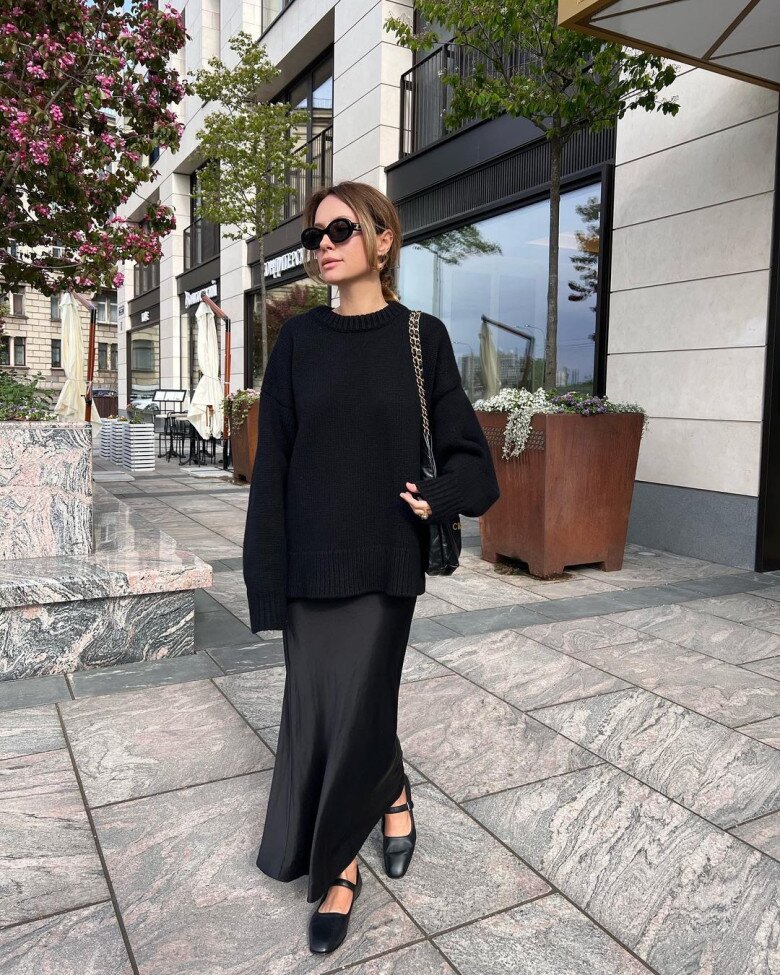 Một bản giao hưởng của sự thanh lịch tối giản – chiếc sweater đen oversized mềm mại kết hợp cùng chân váy lụa thướt tha, tạo nên vẻ ngoài vừa nền nã vừa cuốn hút.