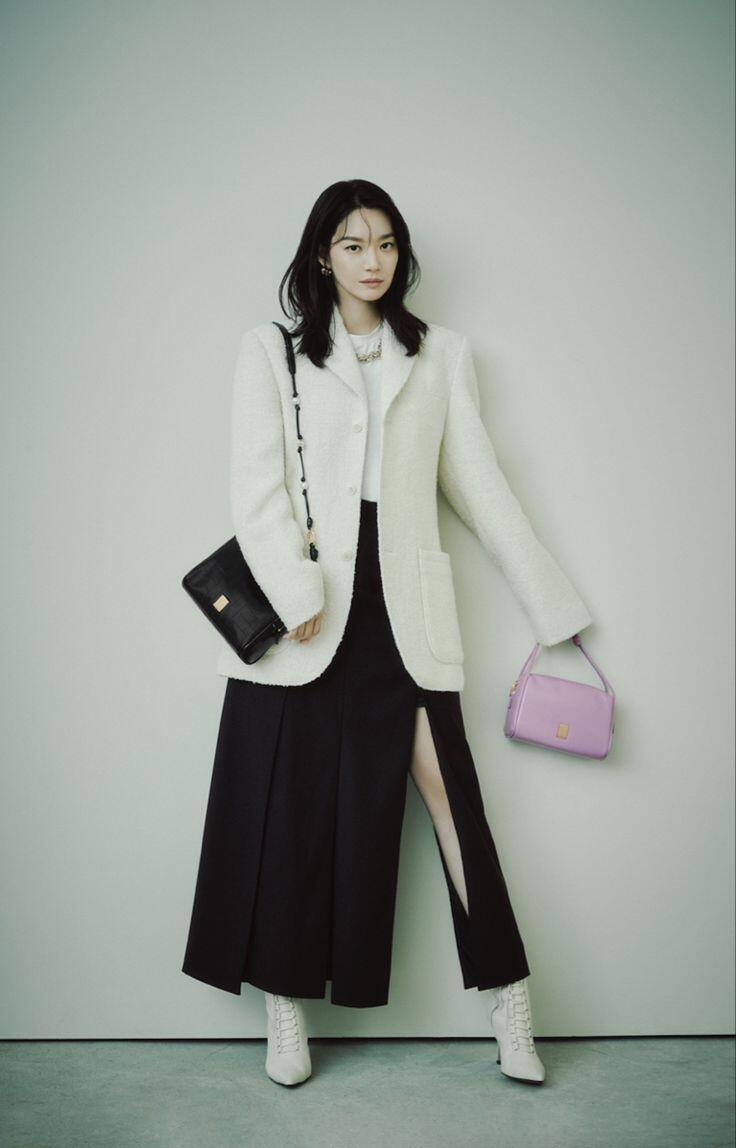 Shin Min Ah khoe vẻ thanh lịch trong blazer trắng phối cùng chân váy xẻ và boots cao cổ, tạo điểm nhấn bằng túi tím pastel nổi bật.