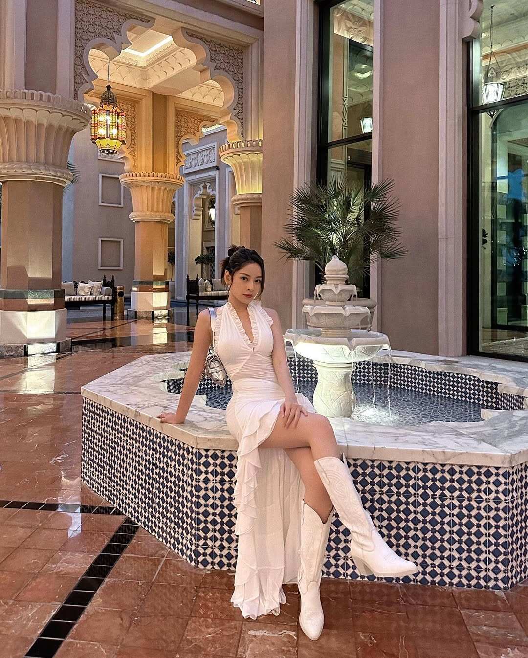 Trong một djp khác, Chi Pu diện váy trắng cổ yếm ôm dáng, phần thân trên gọn gàng tôn vai và eo. Chân váy xếp tầng bèo nhún bất đối xứng tạo độ bay nhẹ. Cô mix boots cao cổ cùng tông, giúp tổng thể vừa nữ tính vừa hiện đại, nổi bật giữa không gian sang trọng.