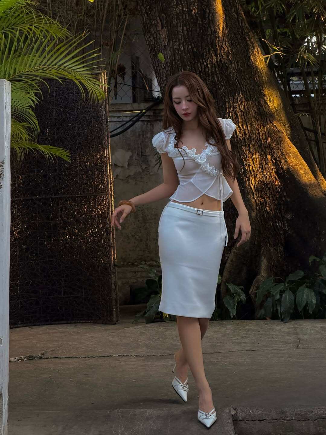 Trong một lần khác, Chi Pu chọn trang phục trắng tinh khôi với áo croptop phối chi tiết bèo nhún ở ngực và vai, kết hợp chân váy bút chì thanh lịch. Bèo nhún giúp outfit thêm điểm nhấn mềm mại và cuốn hút hơn.