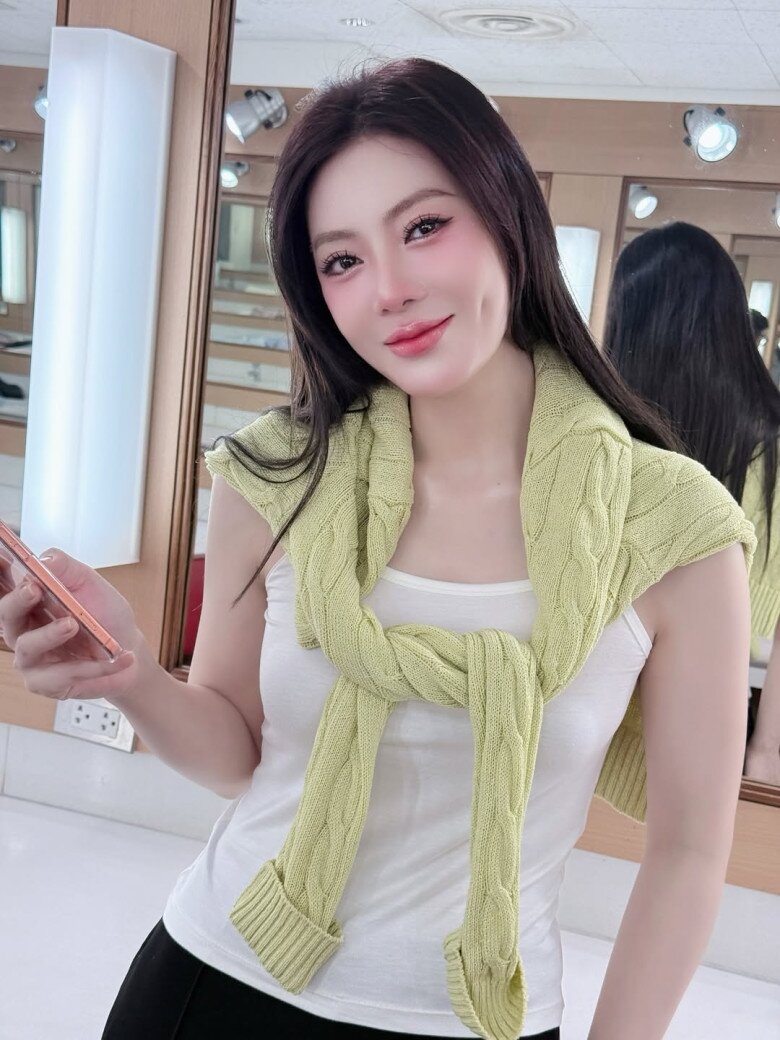 Áo tank top trắng tối giản được nâng tầm bằng chi tiết sweater khoác vai màu xanh nhạt - một công thức layering kinh điển cũng được cô bắt kịp xu hướng.