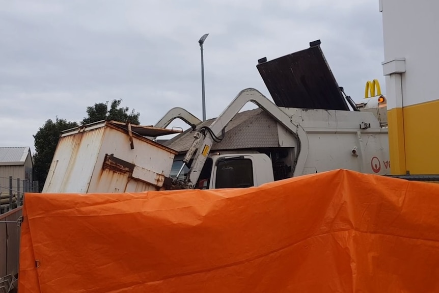 A garbage truck behind a makeshift screen.