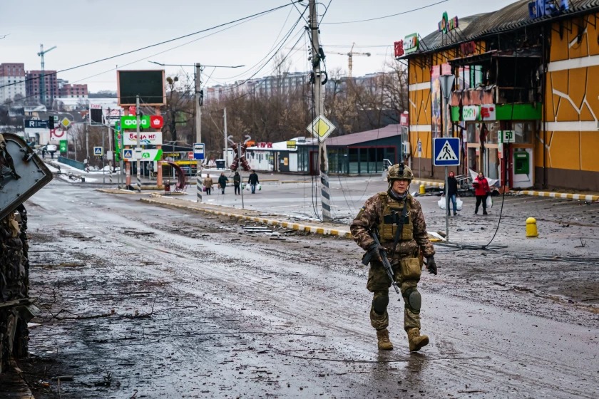 Một binh sĩ Ukraine đi ngang qua một con đường bị thiệt hại sau giao tranh với lực lượng Nga ở ngoại ô Irpin, gần Kyiv vào tháng 3. Ảnh: Los Angles Times