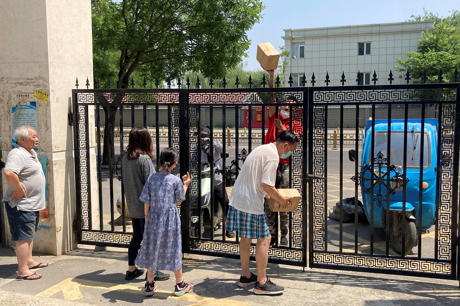 Người chuyển hàng giao bưu kiện qua cổng một khu dân cư ở Bắc Kinh hôm 22/5. Ảnh: Reuters