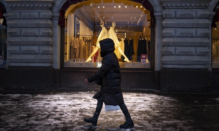 Người phụ nữ bước qua cửa sổ trưng bày tại một cửa hàng ở Quảng trường Đỏ, thủ đô Moskva, Nga, ngày 28/3. Ảnh: AP.