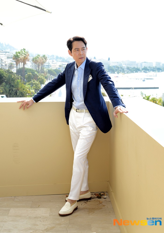 Ở hoạt động bên lề hôm 20/5, sao Hàn kết hợp sơ mi xanh với vest xanh đen, quần trắng và giày lười. Trang phục, phụ kiện của Gucci. Theo Newsen, Lee Jung Jae được săn đón cả trong và ngoài nước. Hồi tháng 1, anh dẫn đầu bảng xếp hạng Diễn viên điện ảnh nổi tiếng tại Hàn, được tạp chí GQ ấn bản Hàn Quốc chọn là Người đàn ông của năm 2021. Ảnh: Newsen