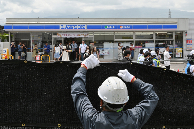 Công nhân lắp đặt lưới chắn view núi Phú Sĩ trên vỉa hè đối diện siêu thị, sáng 21/5. Ảnh: AFP