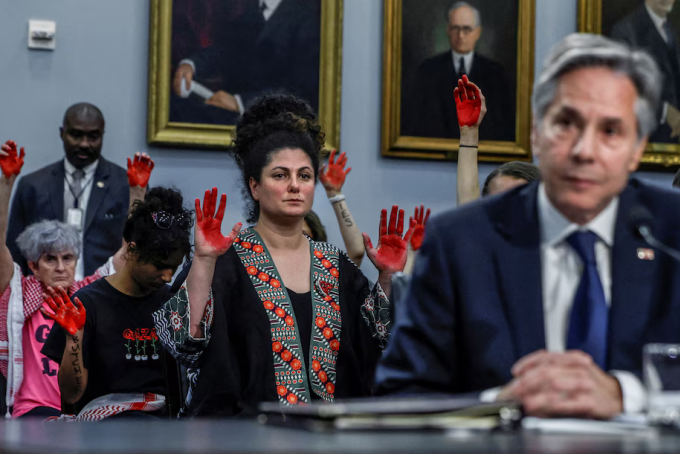 Những người biểu tình ủng hộ Palestine giơ bàn tay sơn đỏ khi Ngoại trưởng Mỹ Antony Blinken trả lời trước phiên điều trần của tiểu ban Phân bổ Ngân sách Hạ viện ngày 22/5. Ảnh: Reuters