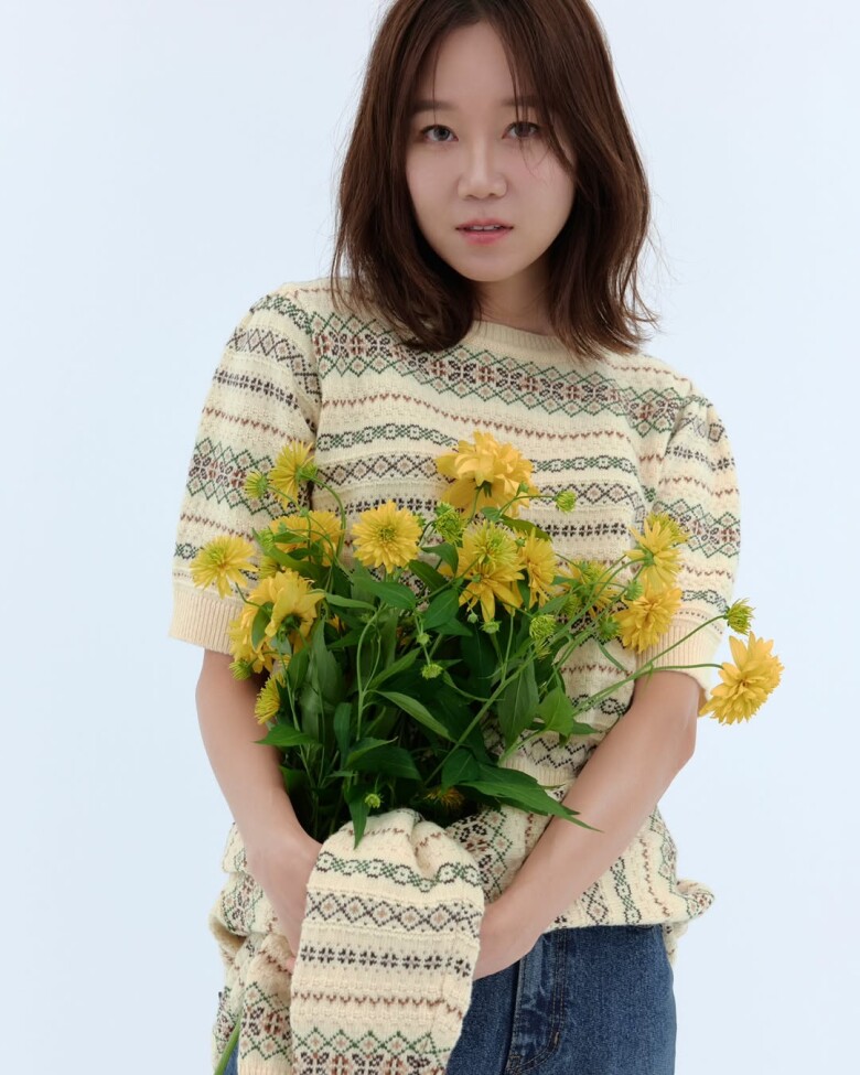 Một chiếc áo len mềm mại đi kèm hoa vàng, hay cách layering tinh tế với sơ mi caro – tất cả tạo nên vẻ ngoài vừa dịu dàng, vừa hiện đại, hoàn toàn không gò bó nhưng vẫn rất cuốn hút.