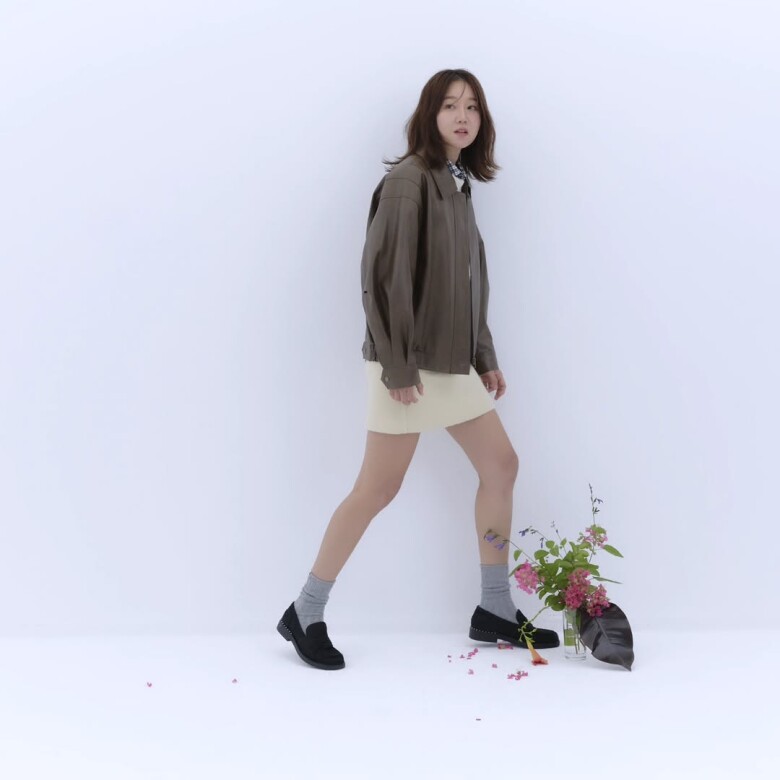 Sự kết hợp giữa áo khoác da mềm, váy ngắn kem và tất cổ cao mang lại vẻ nữ tính hiện đại, phù hợp cả khi đi dạo hay tham dự các sự kiện nhẹ nhàng.