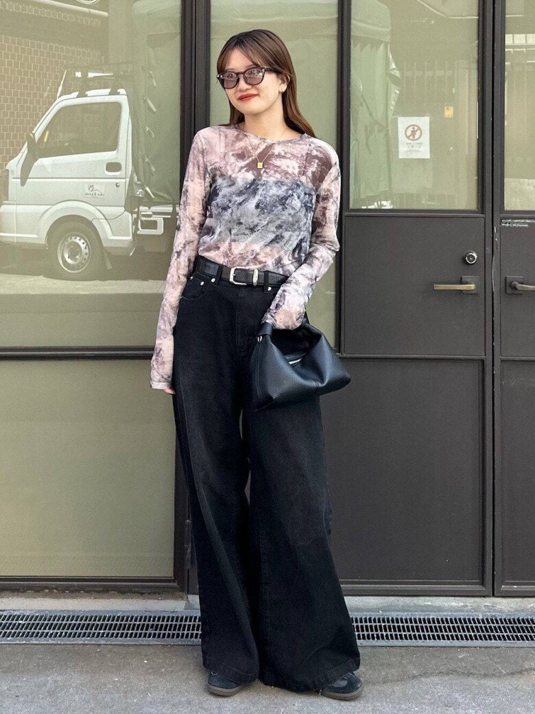 Chiếc quần jeans đen cạp cao là nhân vật chính, với phom dáng rộng bản và chất liệu dày dặn giúp đôi chân trông dài miên man, đặc biệt khi kết hợp cùng giày tối màu và thắt lưng bản vừa tinh tế.