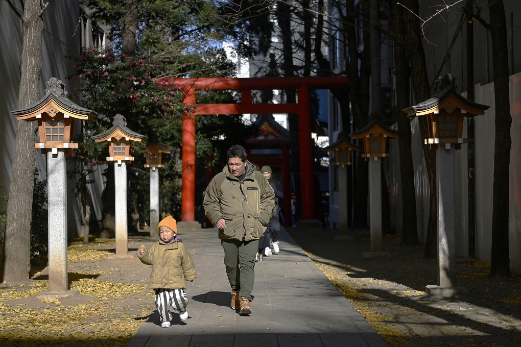 Một người đàn ông đi lễ chùa đầu năm với con trai ở Tokyo, ngày 1/1. Ảnh: AFP