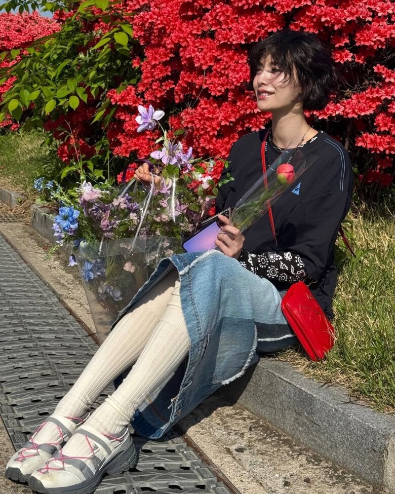 Chân váy denim dài và áo sweater đen, kết hợp giày sneakerina cùng phụ kiện túi đỏ tạo điểm nhấn, Nana tạo nên một bộ cánh street style đậm dấu ấn cá nhân cô - cá tính, năng động nhưng không kém phần điệu dà