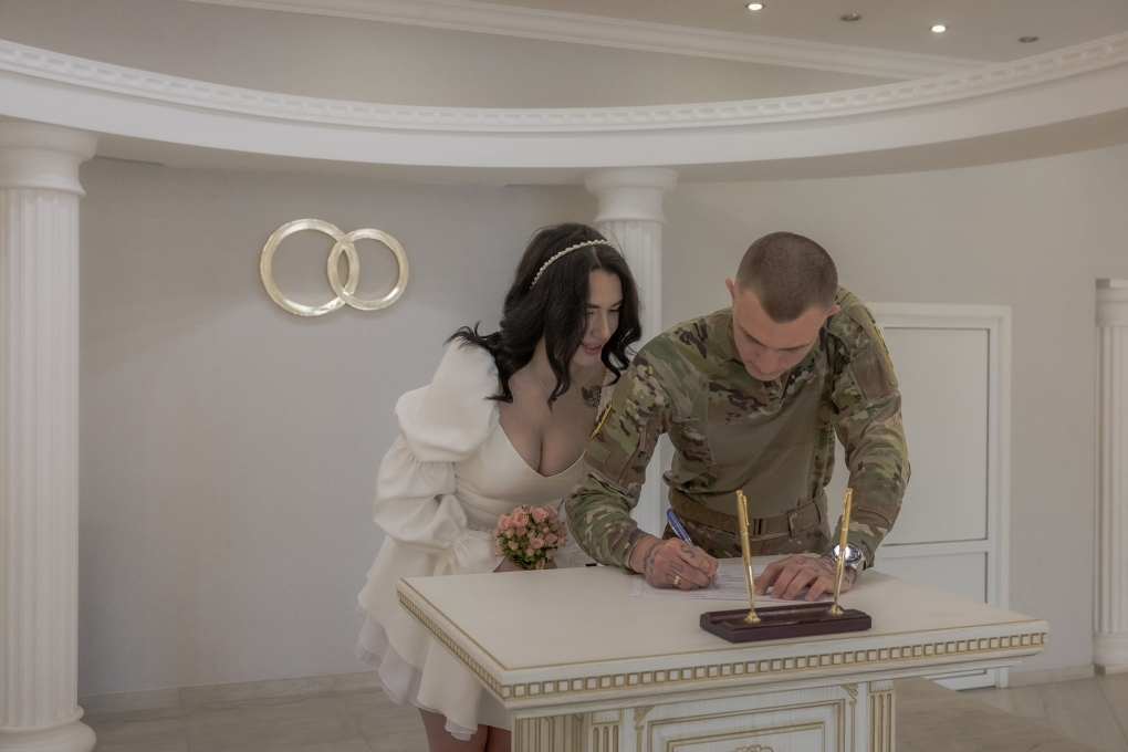 Cô dâu Anna đứng cạnh, nhìn chú rể Pavlo Chornobai kê khai giấy đăng ký kết hôn trong lễ cưới tại văn phòng đăng ký kết hôn ở Sloviansk, Donetsk, ngày 25/4. Ảnh: AFP